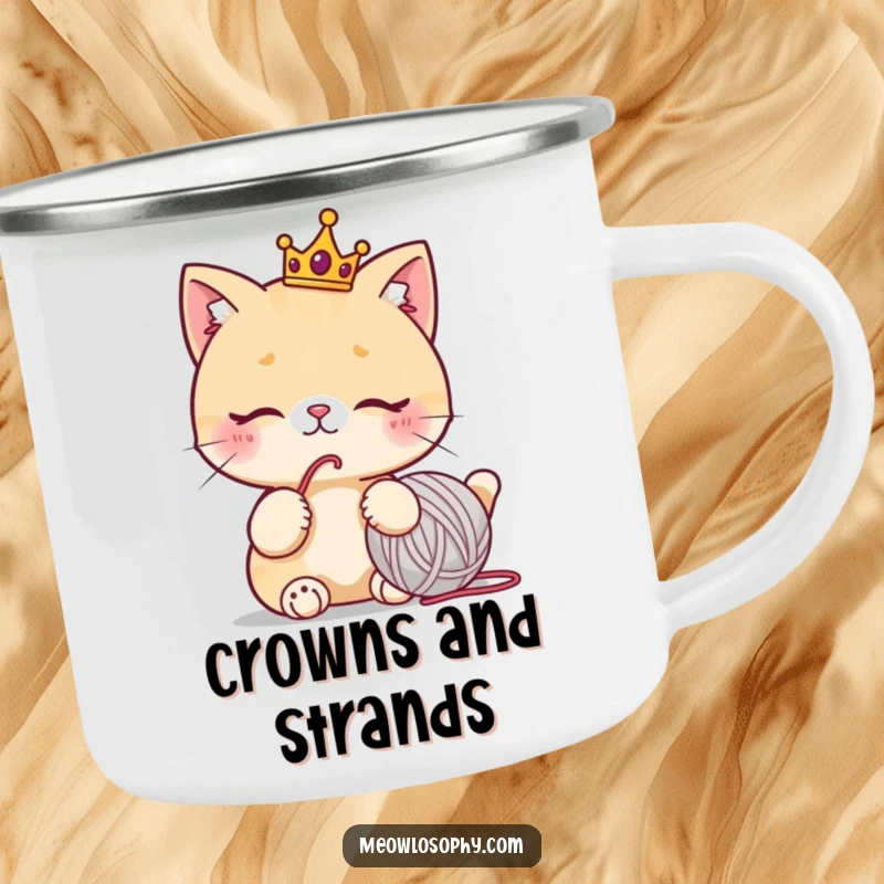 Funny camping mug with a cute cat wearing a tiny crown, thoughtfully staring at a yarn ball, humorous outdoor drinkware.